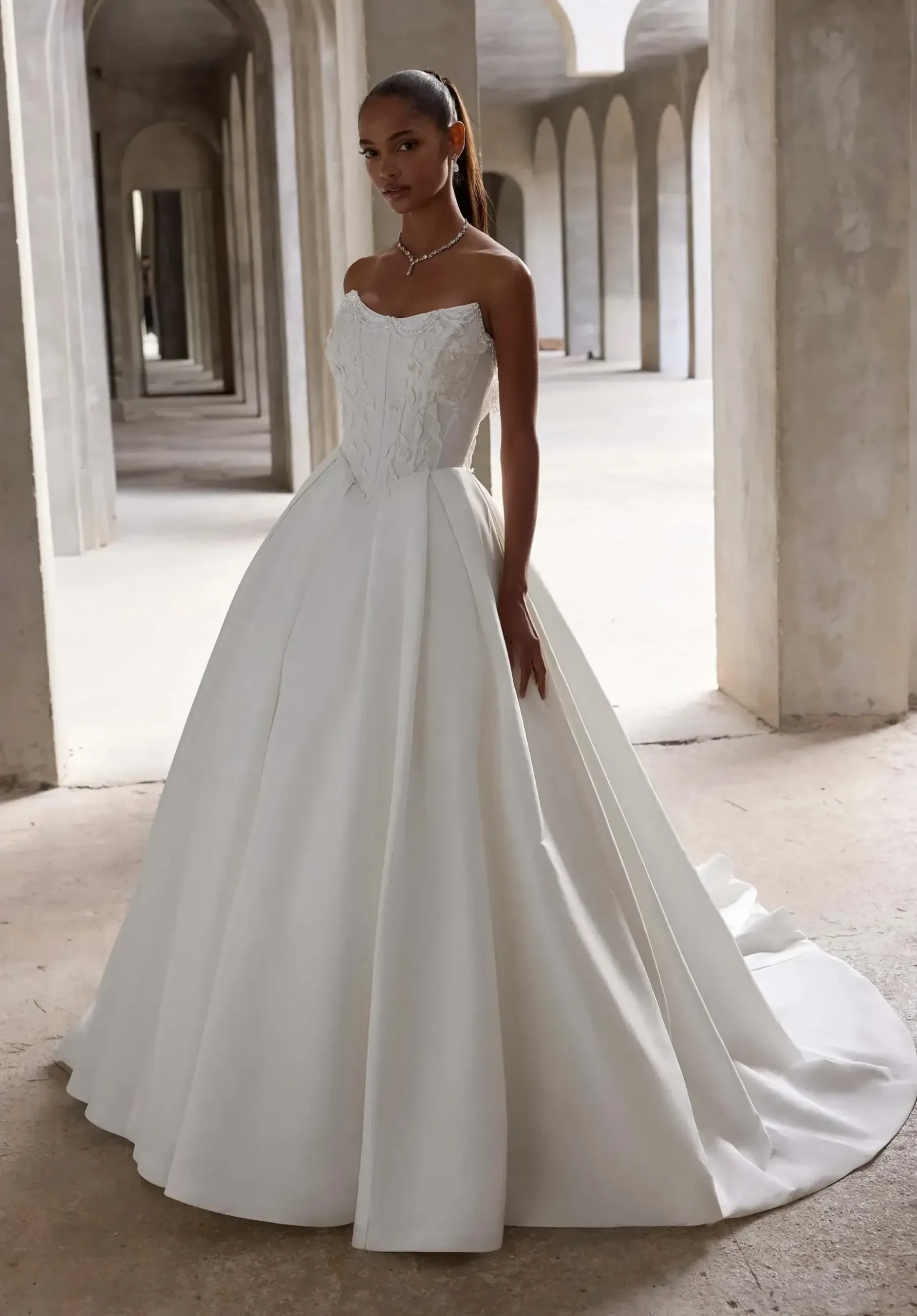 model is wearing a strapless ball gown wedding dress with a basque waist