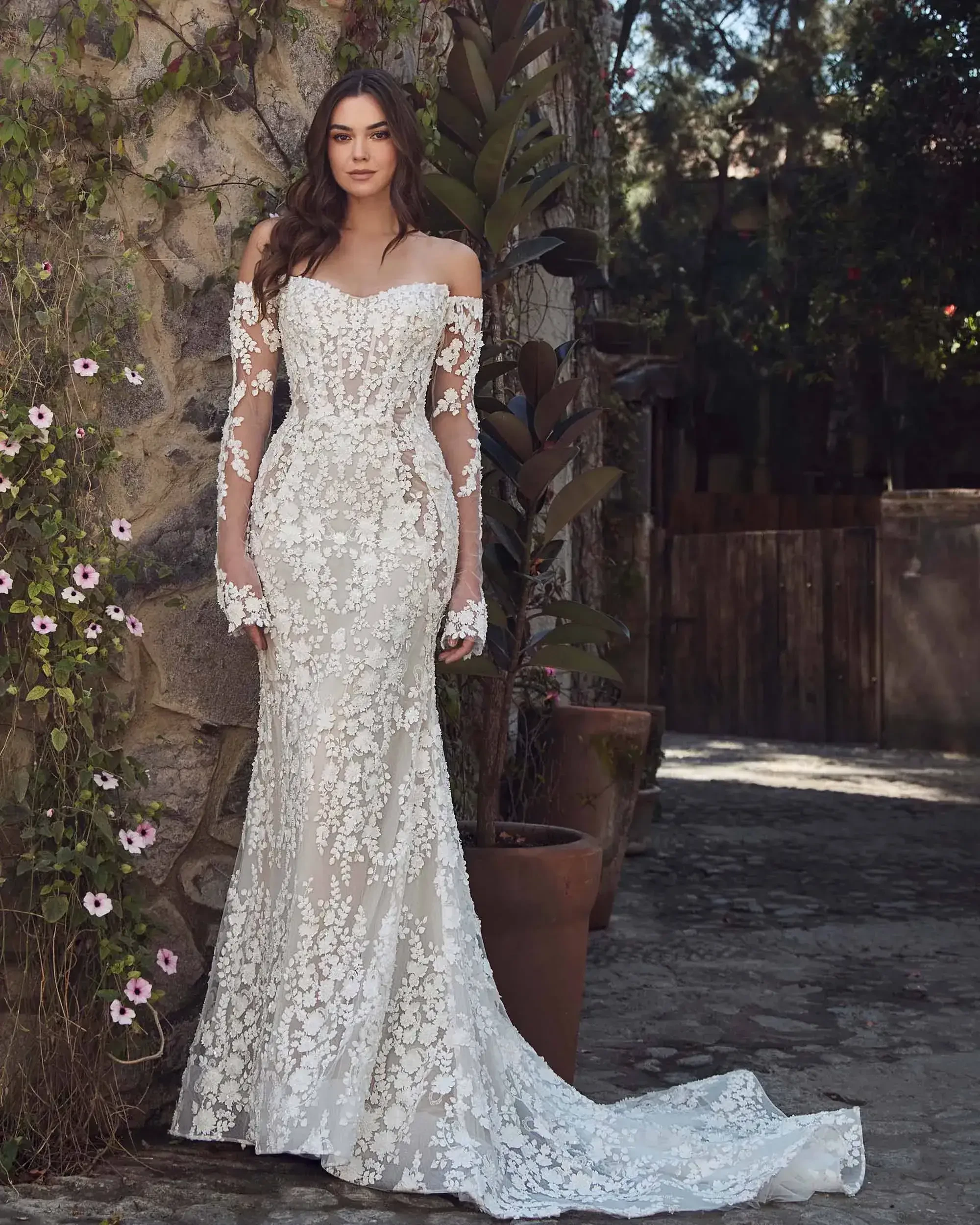 model is wearing a long sleeve off the shoulder fit and flare wedding dress